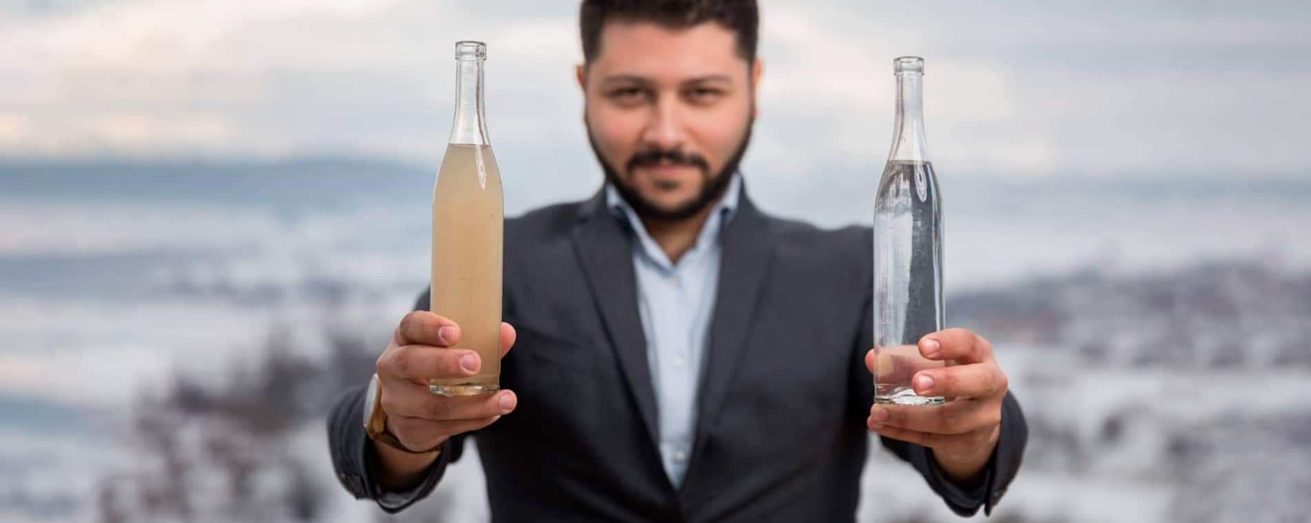 Khaled Al Mezayen compare deux bouteilles d'eau, l'une sale et l'autre parfaitement traitée.